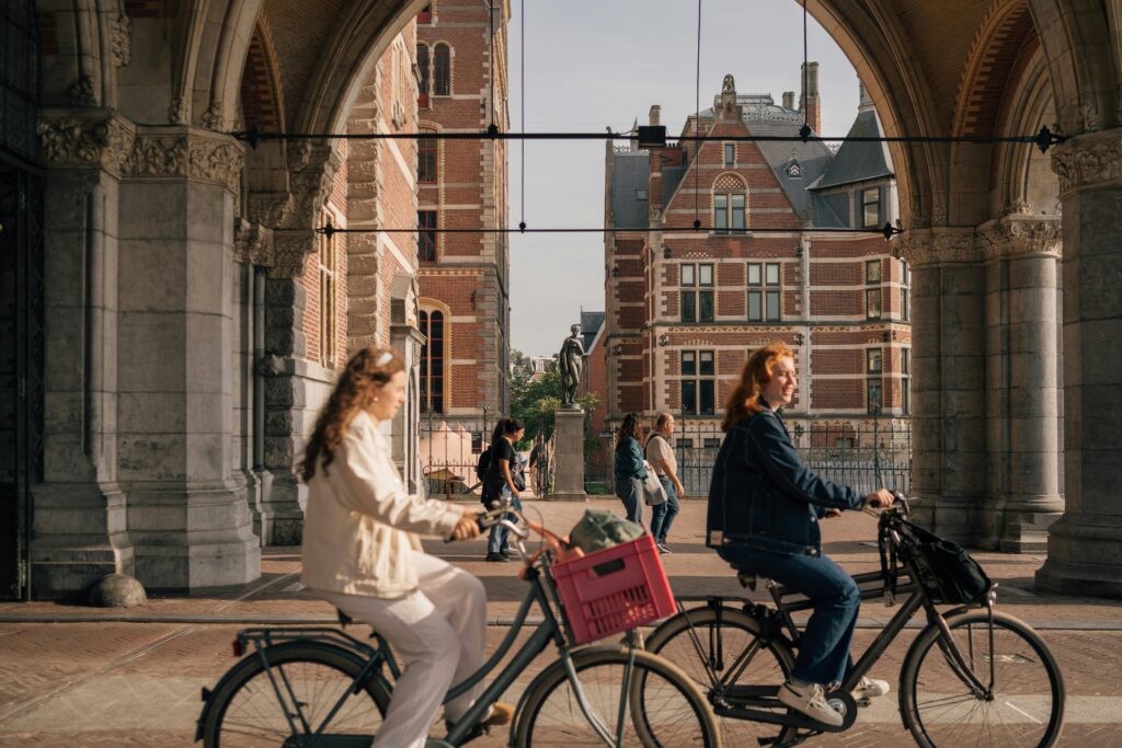 Fietsers onder een historische boog bij een stadsgebouw in Nederland.